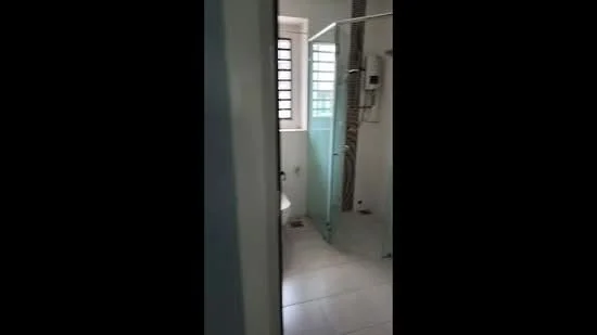 Bathroom features: glass shower enclosure, wall-mounted shower head, toilet, white tiled walls, white tiled flooring, window with louvered shutters, built-in water heater; style: modern.