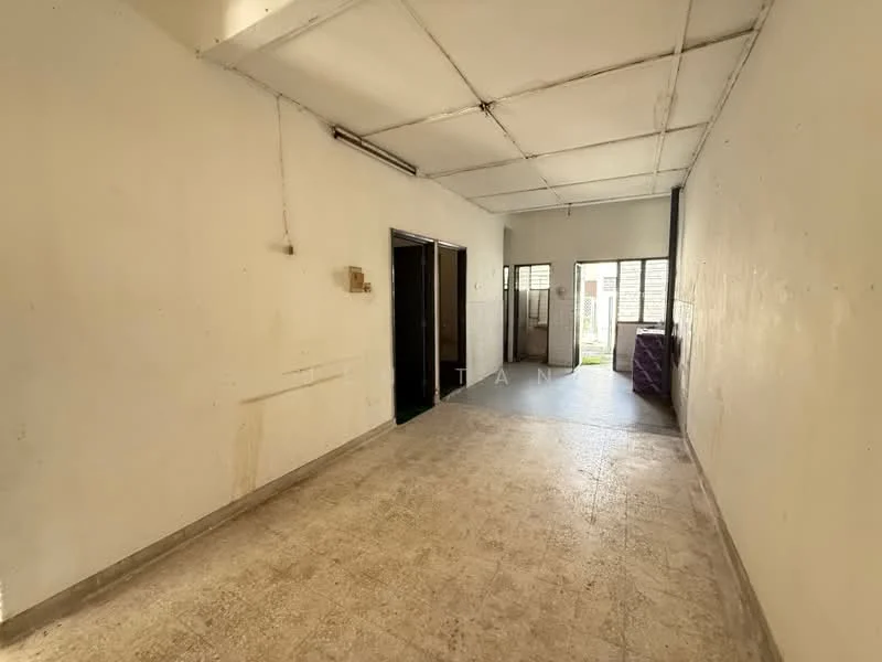 Room features: white painted walls, concrete flooring, exposed ceiling, single door leading to outside, window with grille, light fixture on ceiling, open layout, no visible furniture.