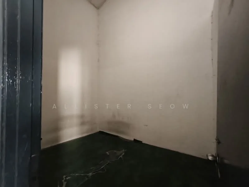 Room features: bare walls, green flooring, corner room, no visible windows, minimal lighting, empty space.