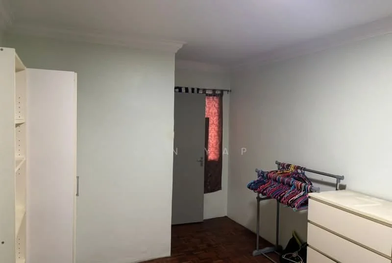 Room features: light green painted walls, wooden flooring, white built-in wardrobe, white chest of drawers, hanging clothes rack with colorful hangers, door with a window, curtains, ceiling with crown moulding.