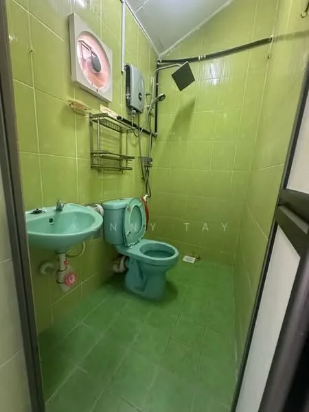 Bathroom features: green tiled walls, green tiled flooring, single-bowl green sink, chrome basin mixer faucet, toilet with water tank, shower head on wall, wall-mounted water heater, metal towel rack.