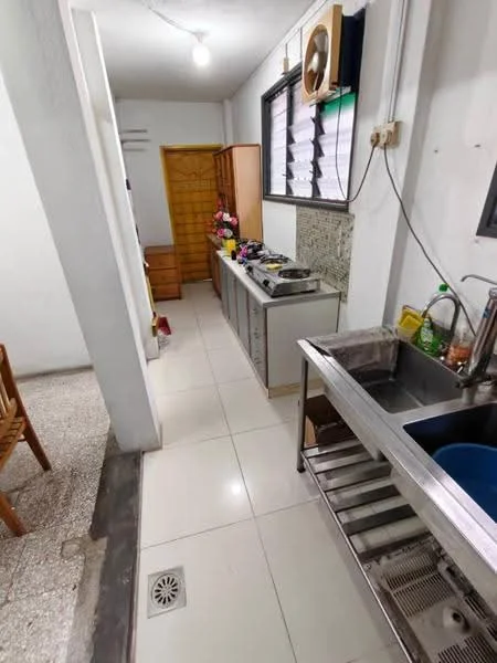Kitchen features: white tiled walls, glossy white floor tiles, stainless-steel sink, chrome pull-down faucet, kitchen cabinets with wood finish, countertop with grey surface, gas stove with multiple burners, exhaust fan, window with blinds, drainage floor grate; style: modern. Room features: wooden dining table, chairs, open layout.