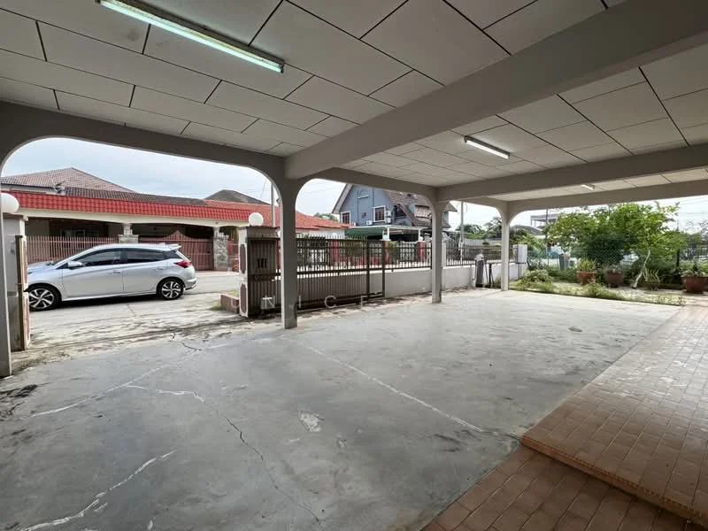 Exterior type: car porch; features: covered car porch, concrete flooring, exposed ceiling with fluorescent lighting, surrounded by fencing, adjacent to residential buildings, landscaped area with potted plants; style: modern.