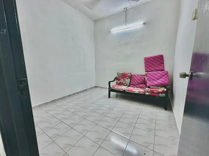 Room features: white painted walls, tile flooring, fluorescent ceiling light, black wooden sofa with floral upholstery, pink cushions, empty space, no visible decor; style: minimalist.
