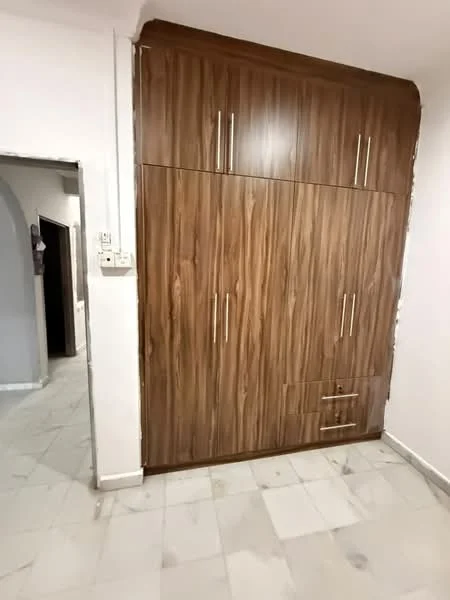 Room features: wooden cabinetry with brown finish, multiple storage compartments, two vertical handles on upper cabinets, one horizontal handle on lower cabinet, marble flooring, white walls; style: modern.