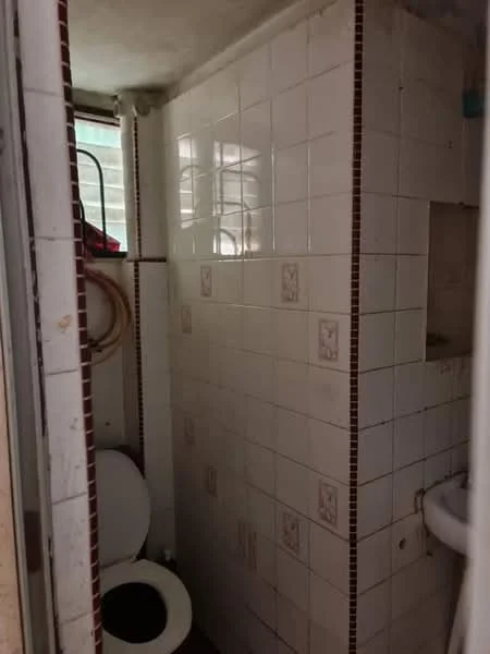 Bathroom features: white tiled walls, ceramic tile flooring, one-piece toilet, sink with faucet, small window for natural light, tiled shower area, decorative tile accents, mirror above sink.