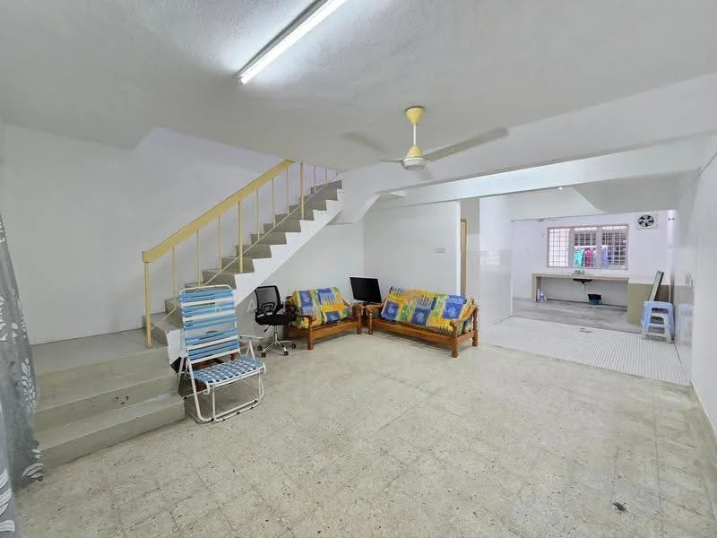 Living features: white painted walls, concrete flooring, 5-blade ceiling fan with light, two wooden sofas with cushions, small black TV on stand, folding chair, staircase with yellow railing, window with metal grille, light fixture on ceiling. Room features: white painted walls, concrete flooring, window with metal grille, work table, plastic chair.