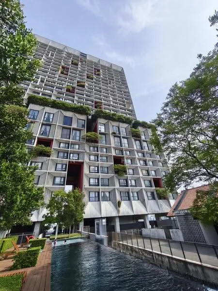 Exterior type: high-rise condominium; features: glass curtain wall, exposed concrete facade, recessed balconies, vertical fins, landscaped terraces, manicured lawn, swimming pool, pool deck with loungers, mature trees, water feature, surrounded by greenery; style: modern.