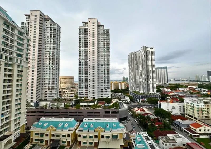Exterior type: high-rise condominium; features: glass curtain wall, white painted facade, approximately 20-storey high-rise, surrounded by mature greenery, urban context with residential buildings, rooftop amenities visible, street view with low-rise houses, city skyline in background; style: modern.