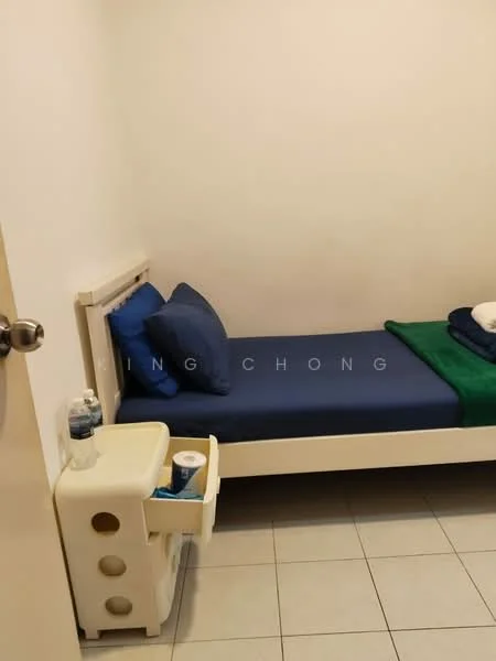 Bedroom features: single bed with white frame, blue and green bedding, two blue pillows, white bedside table with drawer, water bottle on bedside table, ceramic tile flooring, white painted walls, window with no visible treatment.