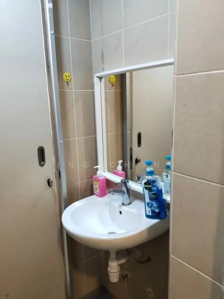 Bathroom features: white ceramic sink, chrome basin mixer faucet, mirror with white frame, beige tiled walls, grey tiled flooring, toiletries on sink, smiley face stickers on wall.