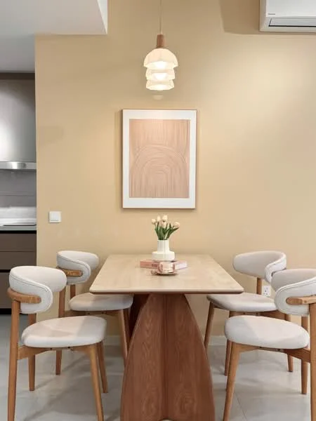 Dining features: wood dining table, 4 upholstered dining chairs, pendant lamp, framed artwork on wall, light yellow painted walls, neutral tile flooring, decorative vase with flowers; style: modern.