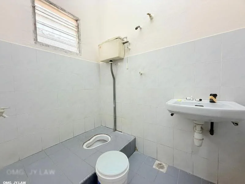 Bathroom features: white tiled walls, grey tiled flooring, squat toilet, sink with faucet, window for ventilation, pipe for water supply, bucket, drainage hole.