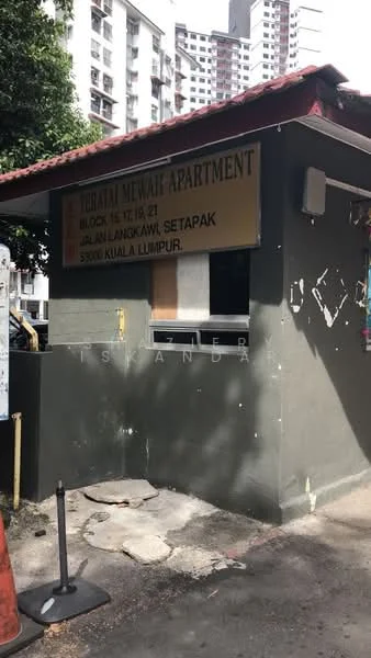 Exterior type: low-rise apartment block; features: signage with apartment name, green painted facade, roof with red tiles, surrounding urban environment, visible residential buildings in background, concrete structure, window openings, entrance area; style: modern.