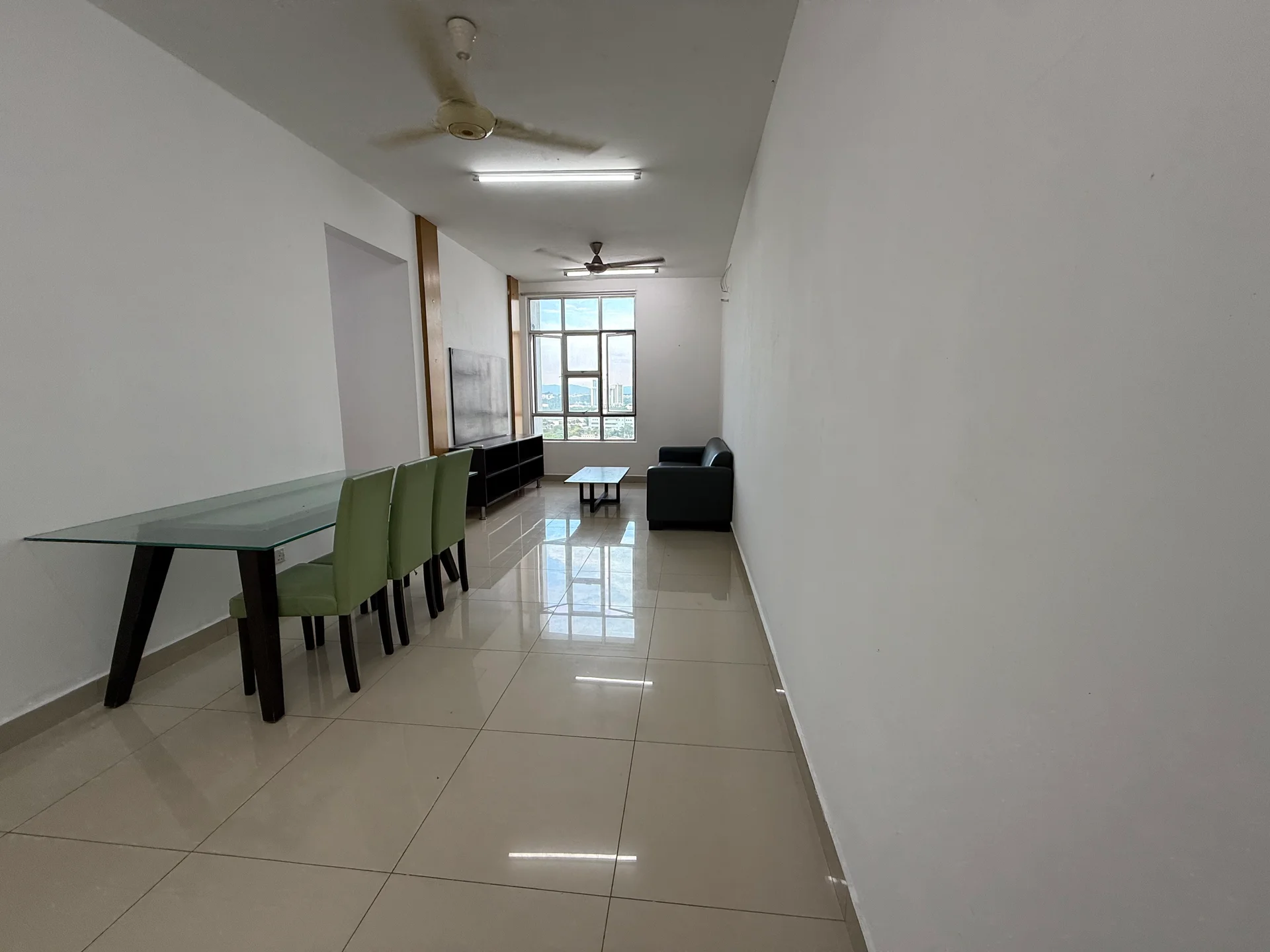 Living features: white painted walls, glossy ceramic tile flooring, 5-blade ceiling fan, recessed downlights, large windows with city view, glass dining table with green chairs, black TV console, 2-seater fabric sofa in dark color, coffee table; style: modern; view: city.