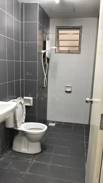Bathroom features: grey tiled walls, white ceramic toilet, white sink, shower with wall-mounted showerhead, small window for ventilation, grey tiled flooring, toilet paper holder, soap dispenser.