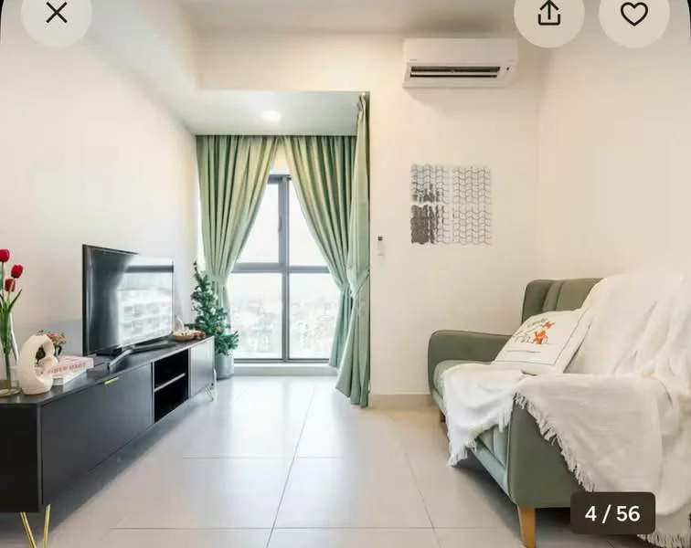 Living features: light grey fabric sofa, white throw blanket on sofa, black TV console, flat-screen TV, green curtains, floor-to-ceiling window, air conditioning unit, decorative wall art, potted plant, ceramic vase with flowers, light-colored tiled flooring, white painted walls; style: modern; view: city.