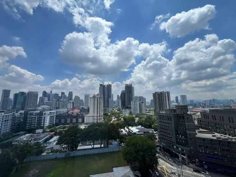 Exterior type: high-rise condominium; features: city skyline view, surrounded by greenery, urban context, multiple high-rise buildings, cloudy sky, open space in foreground; style: modern.