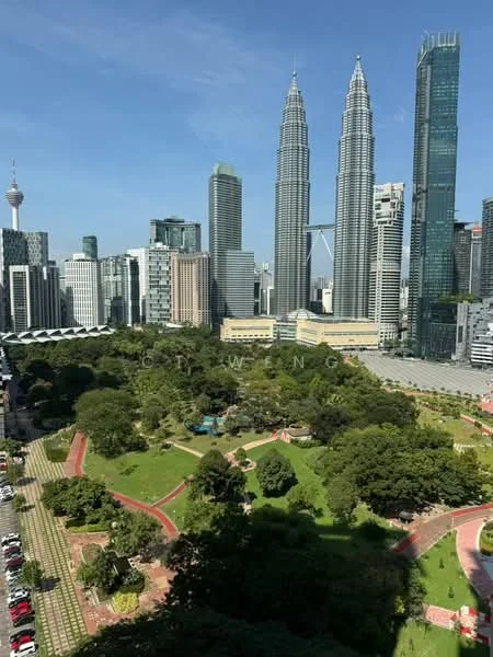 Exterior type: high-rise condominium; features: city skyline view, green park area, surrounded by mature greenery, modern glass facade buildings, Petronas Twin Towers visible, Kuala Lumpur Tower visible; style: modern.