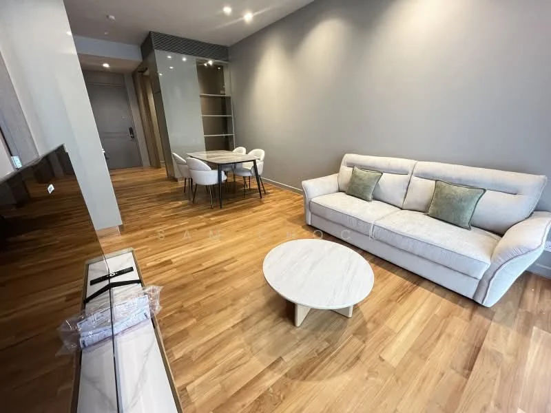 Living features: light grey fabric sofa, 2 decorative cushions, round coffee table with wooden legs, wooden flooring, recessed downlights, wall-mounted TV console, open shelving unit, dining table with white chairs, neutral wall colour, large windows for natural light; style: modern.