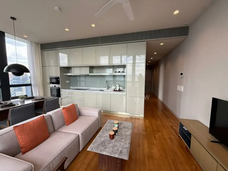 Living features: 3-seater fabric sofa in light grey, orange accent cushions, coffee table with stone top, TV console, wall-mounted TV, wooden flooring, ceiling fan, recessed downlights, floor-to-ceiling windows, open-plan layout with kitchen, decorative wall art, neutral wall colour; style: modern; view: city. Kitchen features: white cabinetry, grey countertop, built-in oven, stainless-steel fridge, stainless-steel sink, chrome pull-down faucet, ceramic tile backsplash, open shelving, induction cooktop, microwave, recessed lighting; style: modern.