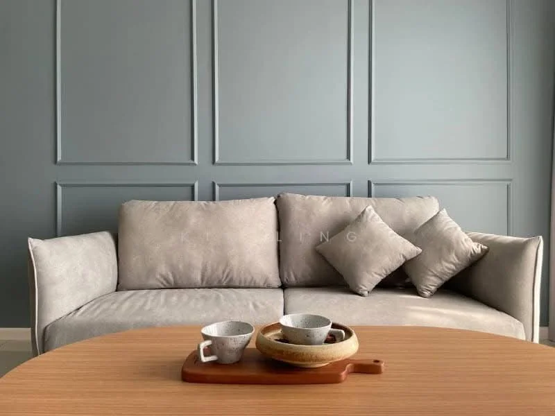 Living features: 3-seater fabric sofa in light grey, decorative cushions, round wooden coffee table, wooden serving tray, ceramic cups, decorative bowl, textured feature wall in blue-grey, neutral flooring; style: modern.