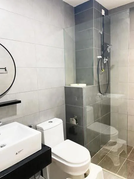 Bathroom features: grey tiled walls, white ceramic sink, black countertop, chrome basin mixer faucet, one-piece toilet, walk-in shower with glass enclosure, chrome shower head, grey tiled flooring, round mirror, wall-mounted shelf; style: modern.