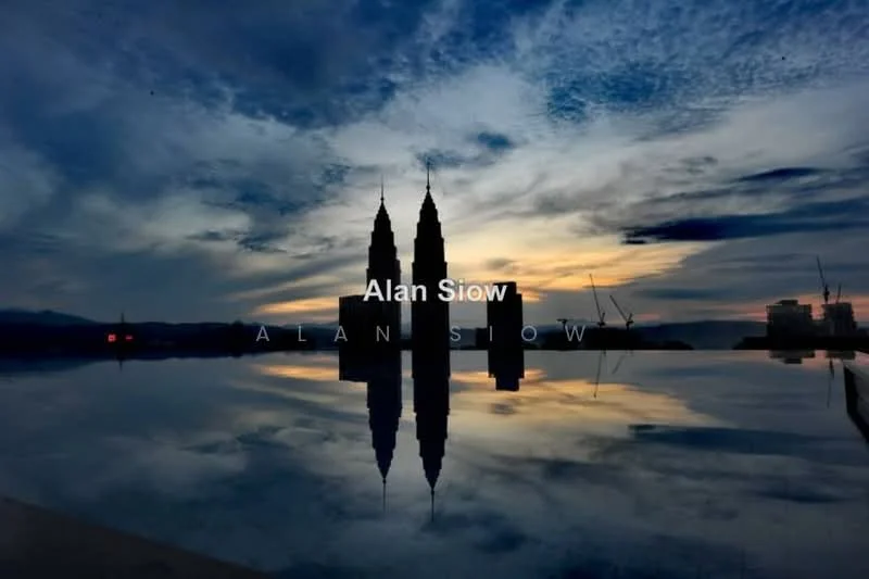 Exterior features: city skyline, reflection in water, twilight sky, silhouette of towers, construction cranes in background; style: modern.