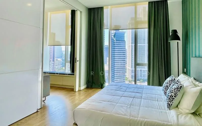 Bedroom features: king-size bed, upholstered headboard, bedside lamps, floor-to-ceiling windows, green curtains, wooden flooring, decorative throw pillows, built-in wardrobe, city skyline view; style: modern; view: city.