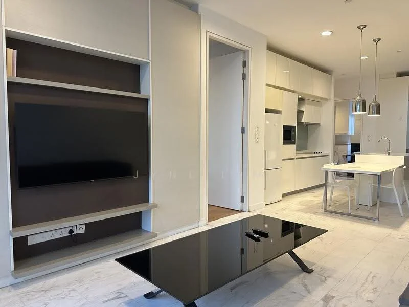 Living features: white painted walls, light wood flooring, built-in TV console, wall-mounted TV, black glass coffee table, dining table with white surface, 4 dining chairs, pendant lighting above dining area, kitchen cabinetry, stainless-steel appliances; style: modern.