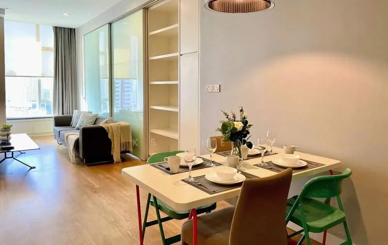 Dining features: white dining table, 4 dining chairs in green and beige, table setting with plates and glasses, pendant light fixture, wooden flooring, built-in shelving unit, large window with city view, decorative plant on table; style: modern; view: city. Living features: grey fabric sofa, throw pillows, coffee table, floor-to-ceiling windows, curtains, wooden flooring; style: modern; view: city.