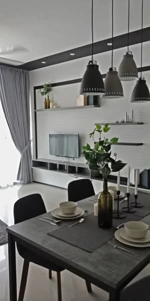 Dining features: 4-seater dining table, black dining chairs, grey table runner, ceramic plates, glass vase with greenery, candlestick holder with candles, wall-mounted TV, open shelving unit, pendant lighting with black shades, floor-to-ceiling curtains, white walls, polished tile flooring; style: modern.