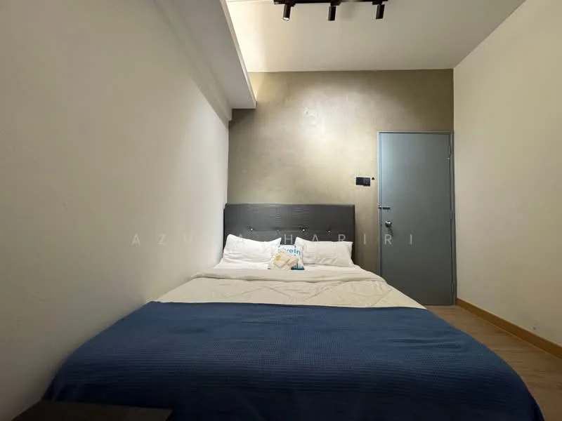 Bedroom features: queen-size bed, upholstered headboard, white bedding, blue throw blanket, grey accent wall, wood flooring, recessed ceiling lights, wall-mounted light switch, door with handle, decorative pillows; style: modern.