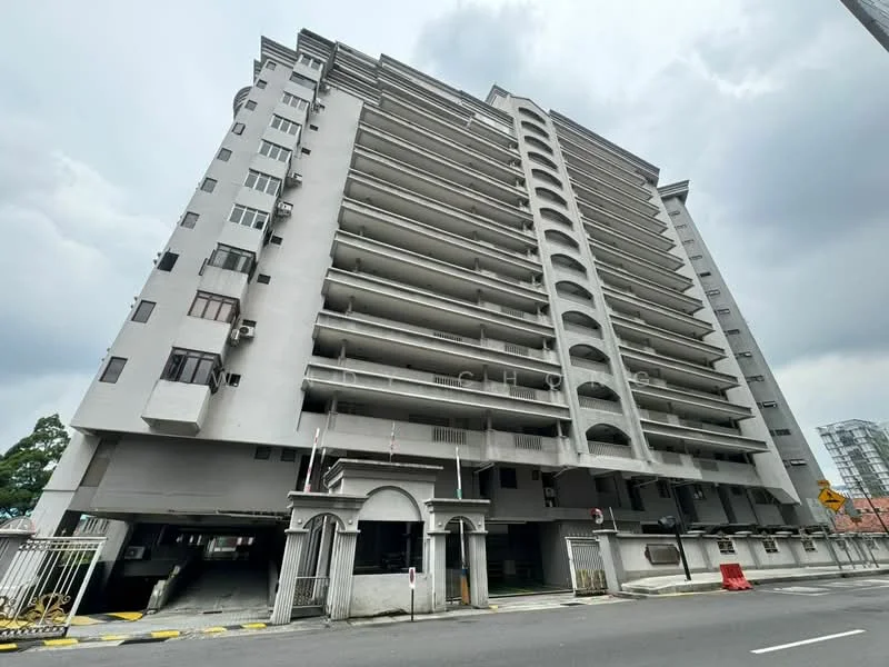 Exterior type: mid-rise condominium; features: grey painted facade, balconies with arches, multiple floors, ground-level parking area, security gate at entrance, visible air conditioning units, surrounded by road, urban context; style: modern.