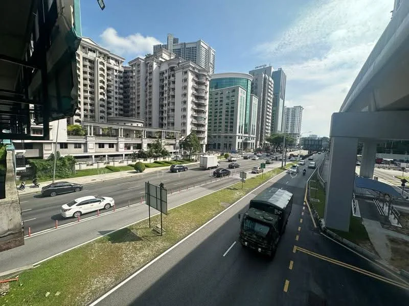 Exterior type: high-rise condominium; features: glass curtain wall, concrete facade, surrounded by mature greenery, urban context with main road, multiple high-rise buildings, open-air parking lot, sidewalk along the road; style: modern.