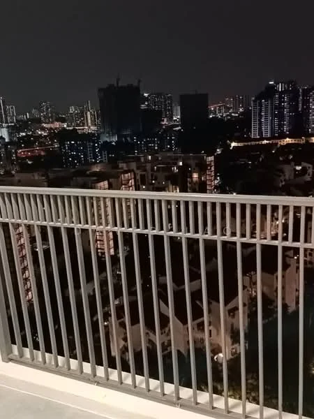 Room features: balcony with metal railing, city skyline view, nighttime lighting, concrete flooring, surrounding buildings visible; view: city.