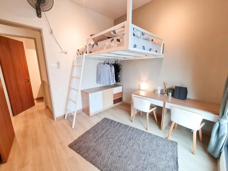 Bedroom features: lofted bed with white frame, desk with wooden surface, two white upholstered chairs, grey area rug, wooden storage cabinet with drawers, clothes hanging rack, wall-mounted fan, light-colored painted walls, laminate flooring, window with natural light; style: modern.