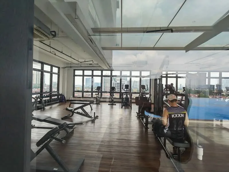 Room features: large windows, wooden flooring, various gym equipment, weight benches, cardio machines, mirrored wall, open layout, city view, high ceiling, air conditioning units, exercise mats, water cooler; style: modern; view: city.