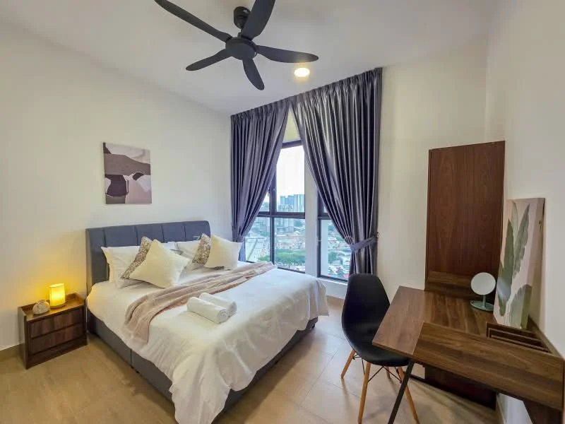 Bedroom features: king-size bed with upholstered headboard, white bedding with decorative pillows, 2 bedside lamps, wooden bedside table, wooden study desk, chair, floor-to-ceiling window, grey curtains, 5-blade ceiling fan, light fixture, decorative artwork on wall, wooden cabinet; style: modern; view: city.