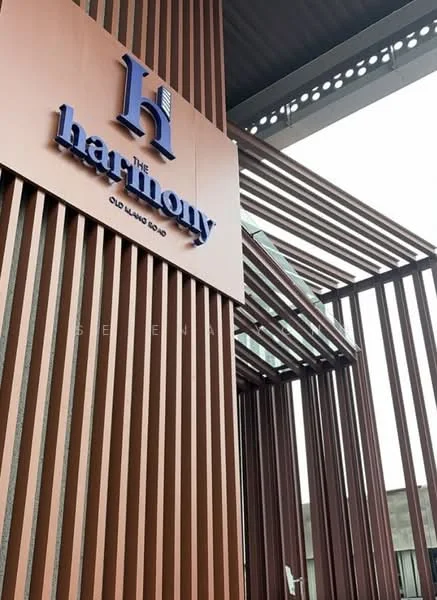 Exterior features: brown wooden slats, metallic signage, glass entrance, modern architectural design, overhang roof, vertical fins, surrounding structure, urban context; style: modern.
