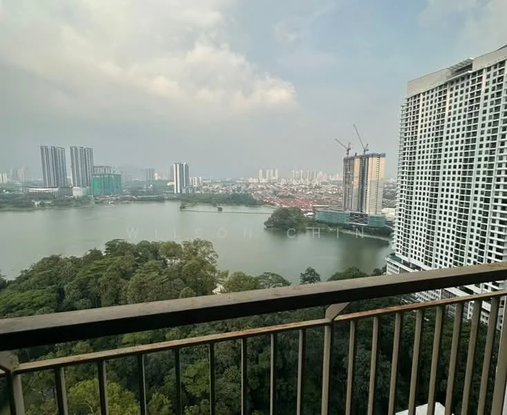 Exterior type: high-rise condominium; features: lake view, city skyline in background, surrounded by greenery, balcony railing, multiple high-rise buildings, construction cranes visible; style: modern.