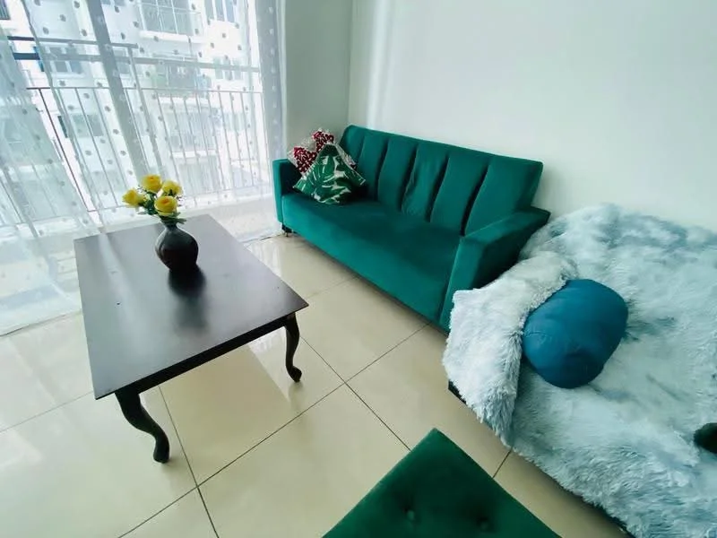 Living features: teal fabric sofa, white throw blanket, blue cushion, black coffee table, large floor-to-ceiling window, sheer white curtains, decorative throw pillows, glossy tiled flooring, vase with yellow flowers; style: modern; view: city.