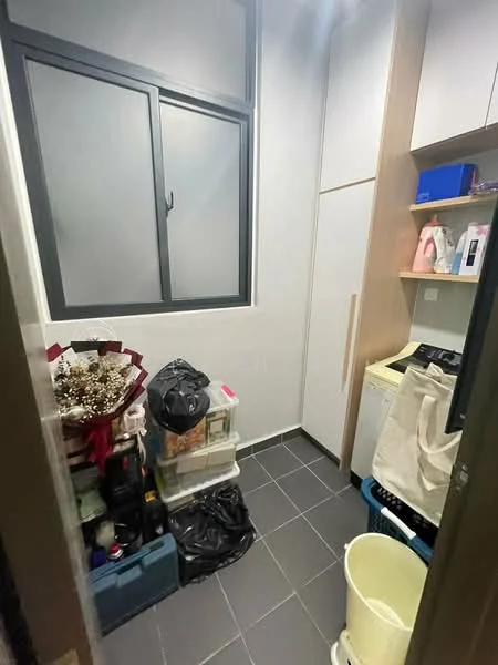 Laundry features: grey tiled flooring, white painted walls, single window with black frame, built-in cabinetry, countertop space, washing machine, storage boxes, plastic bags, decorative items, bucket.