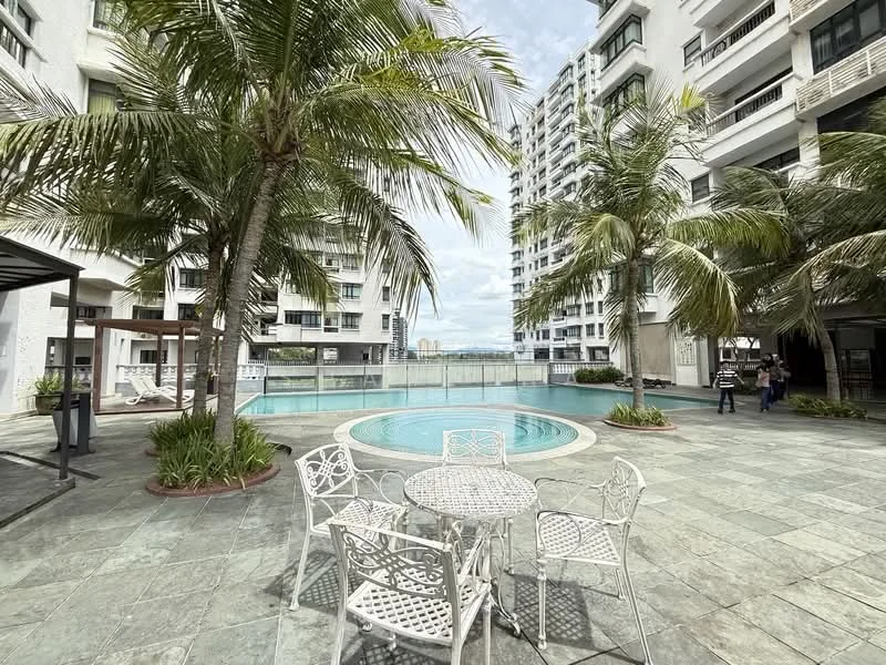 Exterior type: high-rise condominium; features: infinity pool, pool deck with loungers, landscaped garden with palm trees, stone-paved walkway, outdoor dining area with white metal furniture, surrounding high-rise buildings, clear sky, manicured lawn; style: modern.