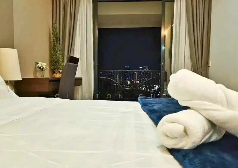 Bedroom features: king-size bed with white bedding, upholstered headboard, nightstand with lamp, wooden desk, chair, floor-to-ceiling windows, curtains, city skyline view, rolled towels, decorative plant, blue throw blanket; style: modern; view: city.