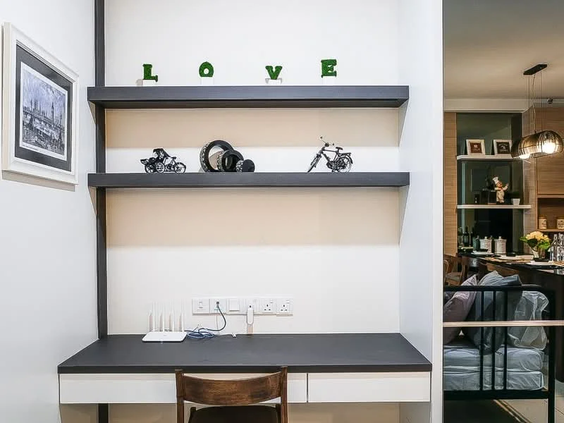 Study features: white painted walls, dark countertop, wooden chair, open shelving, decorative items on shelves, wall-mounted electrical outlets, minimalist design, decorative letters spelling 'LOVE'; style: modern.