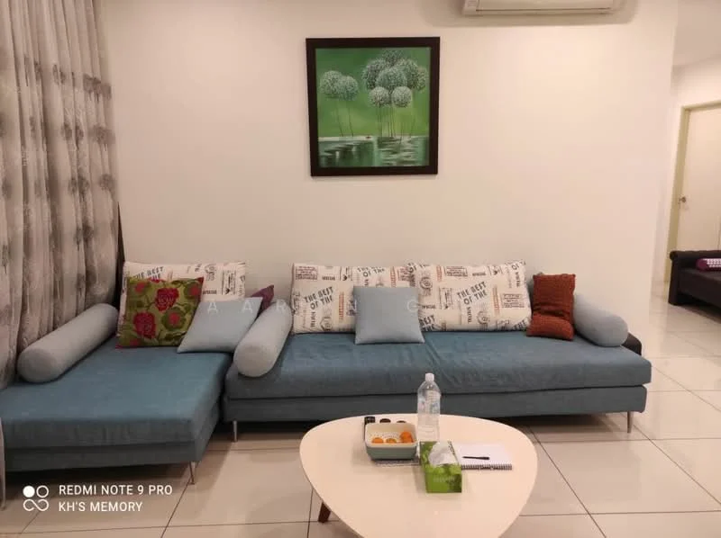 Living features: L-shape sectional sofa in blue fabric, decorative cushions with various patterns, coffee table with round top, water bottle on table, framed artwork with green trees, white painted walls, tile flooring, wall-mounted air conditioning unit, curtains with floral pattern, light-colored door frame; style: modern.