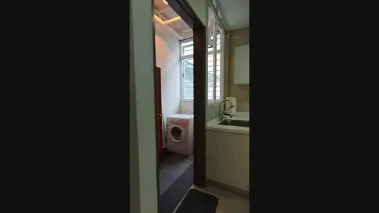 Laundry features: washing machine, sink with faucet, window with louvered design, grey flooring, white cabinetry, countertop, light fixture, doorway leading to another room.