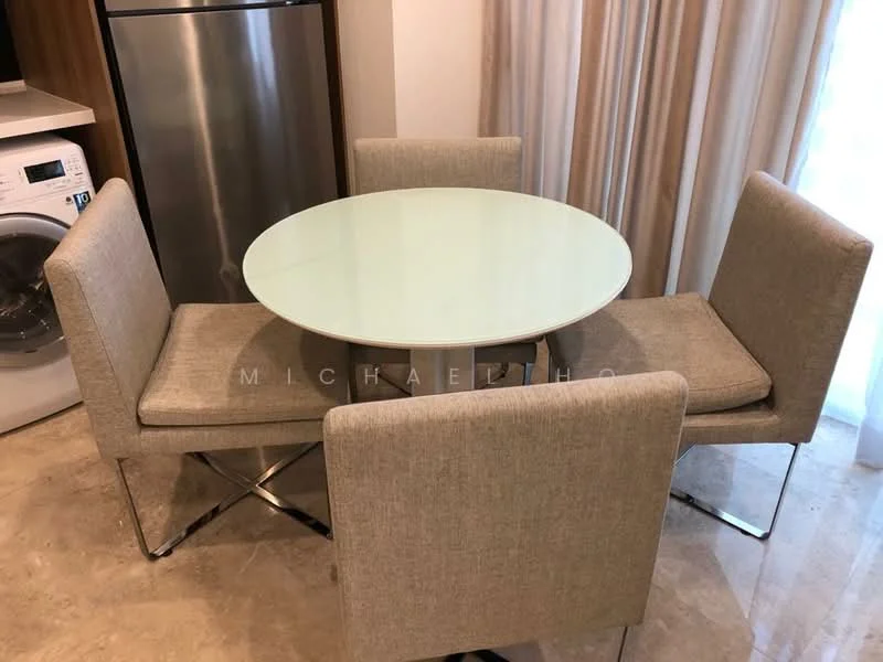 Dining features: round glass dining table, 4 upholstered dining chairs in beige, chrome legs on chairs, marble tile flooring, curtains in light fabric, refrigerator visible in background, washing machine visible in background; style: modern.