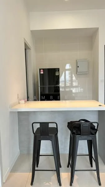 Kitchen features: black refrigerator, white countertop, grey cabinetry, bar stools in black, white tiled backsplash, grey tiled flooring, wall-mounted electrical panel, open layout, under-cabinet lighting; style: modern.